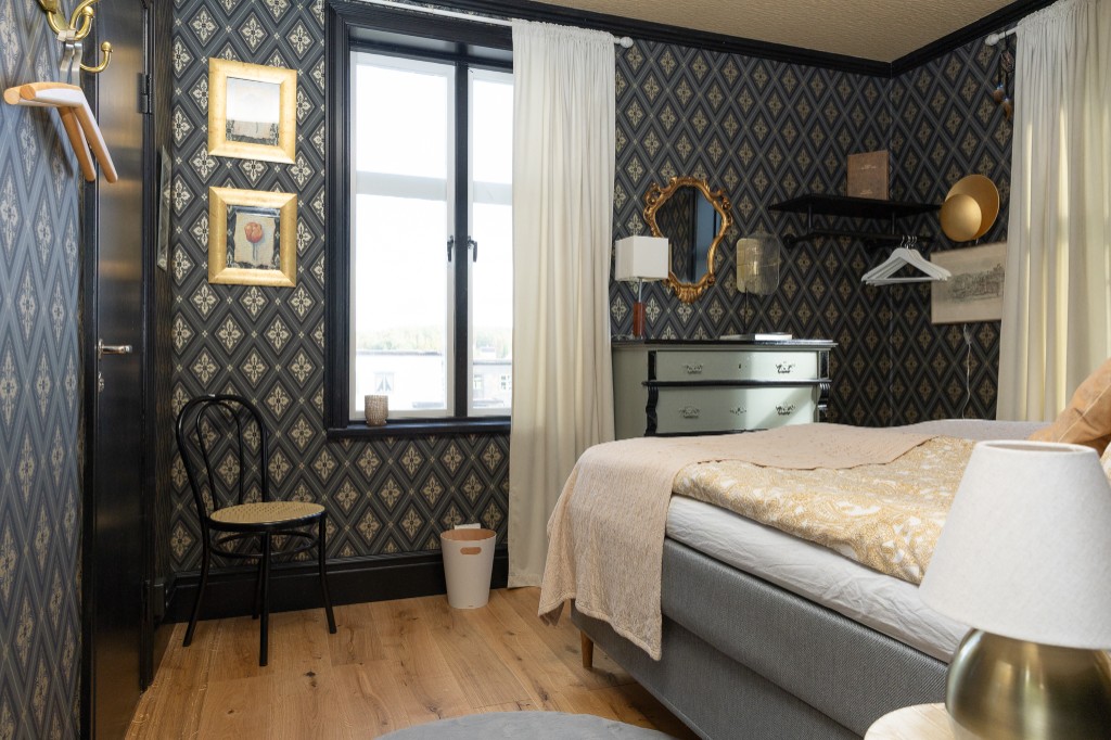 Hotelzimmer mit dunkler Tapete und Goldrahmen